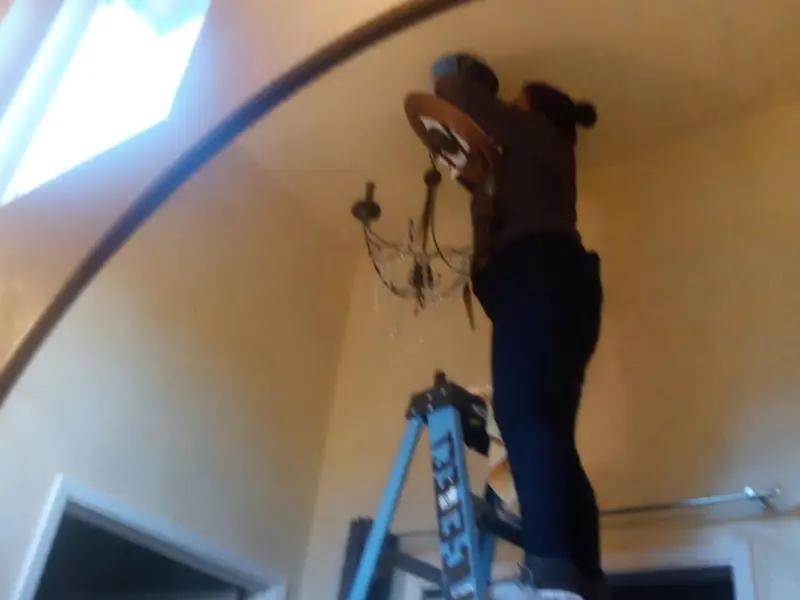 Electrician installing a chandelier in a Old Town residence